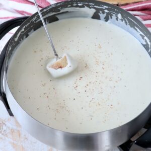piece of bread dipped into cheese fondue in pot